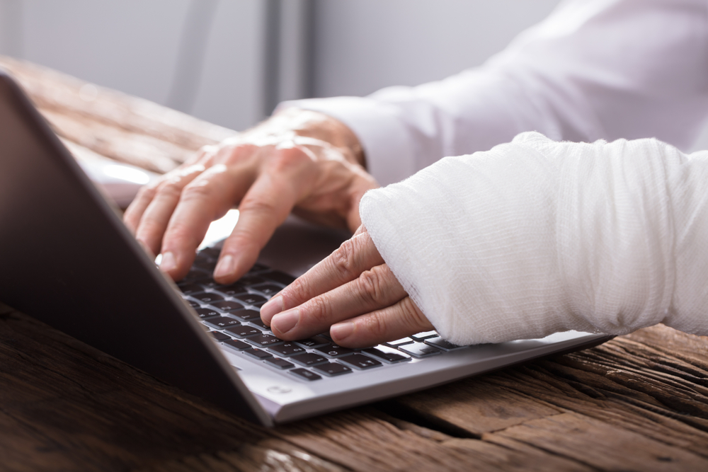 Photo of Hand Injured Man Using Laptop