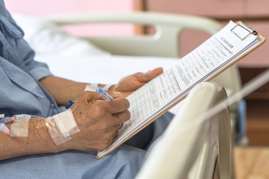 A Person On The Hospital Bed Filling Out Paperwork