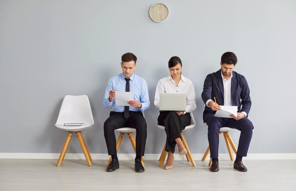 Group of male and female job seekers sitting in row on chairs waiting for job interview.