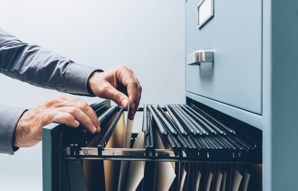 Lawyer searching for records into a filing cabinet drawer close up
