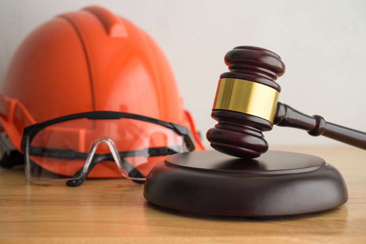Hammer judge gavel with construction hat helmet, worker safety glasses on wooden background.